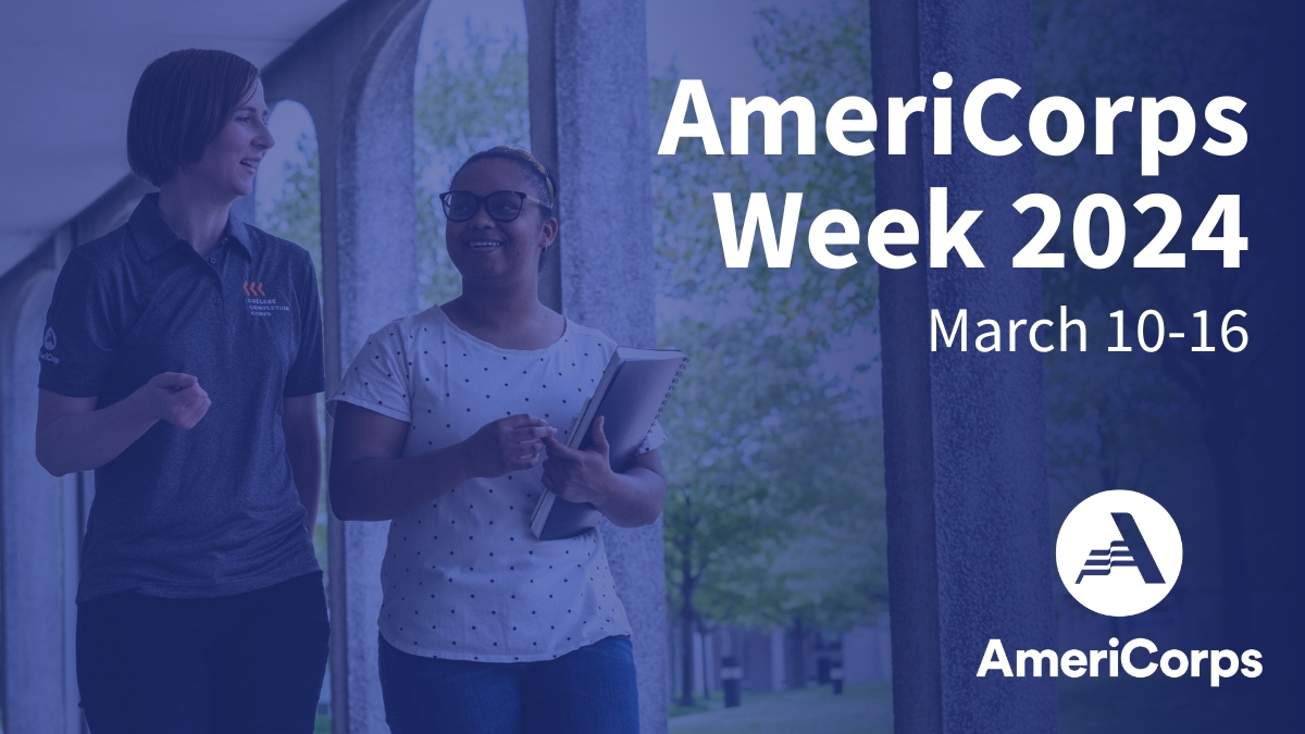 An AmeriCorps member walking with a college student on campus.