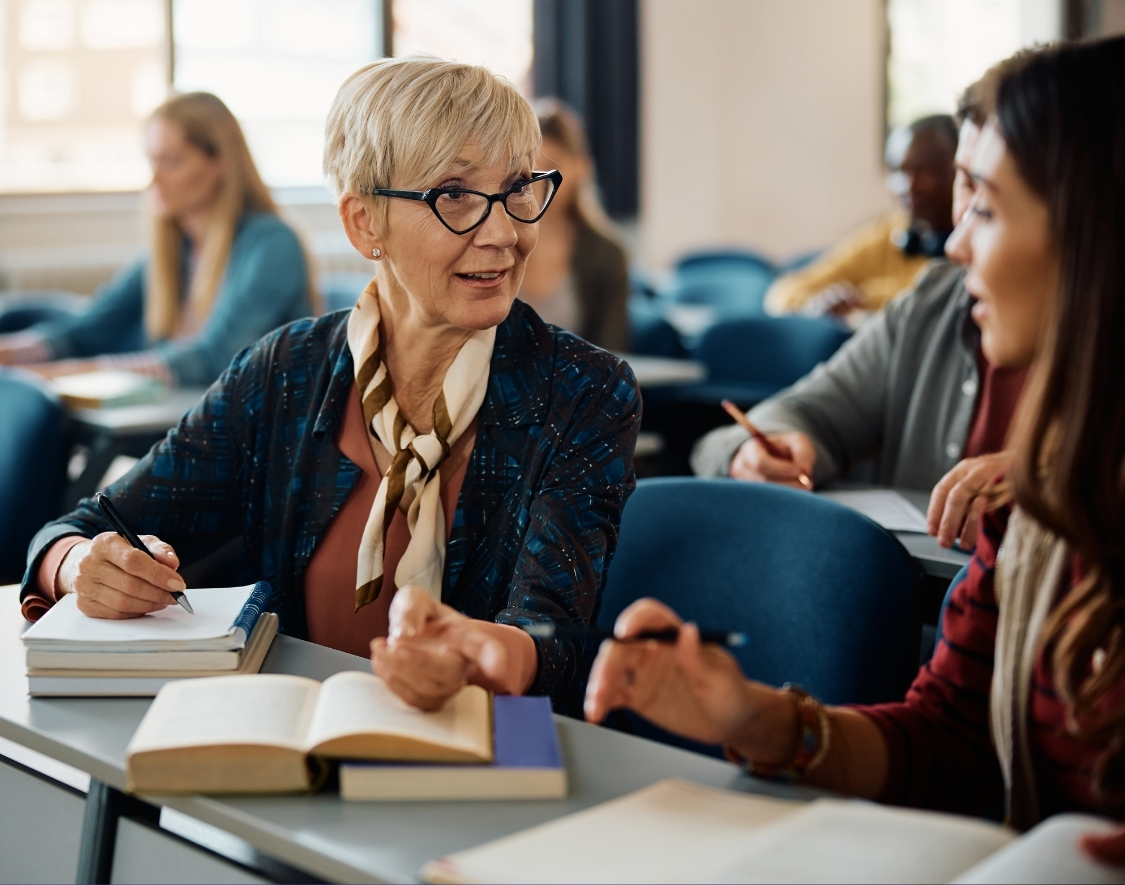 An adult in a classroom talking to another student